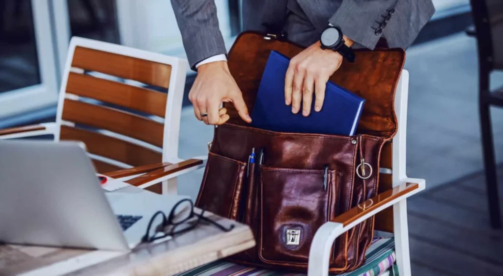 person keeping documents in brown backpack