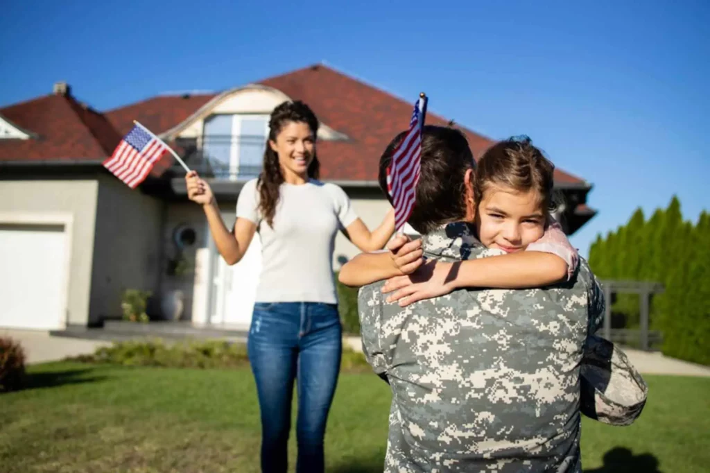 military man hugging girl with USA flag in hand